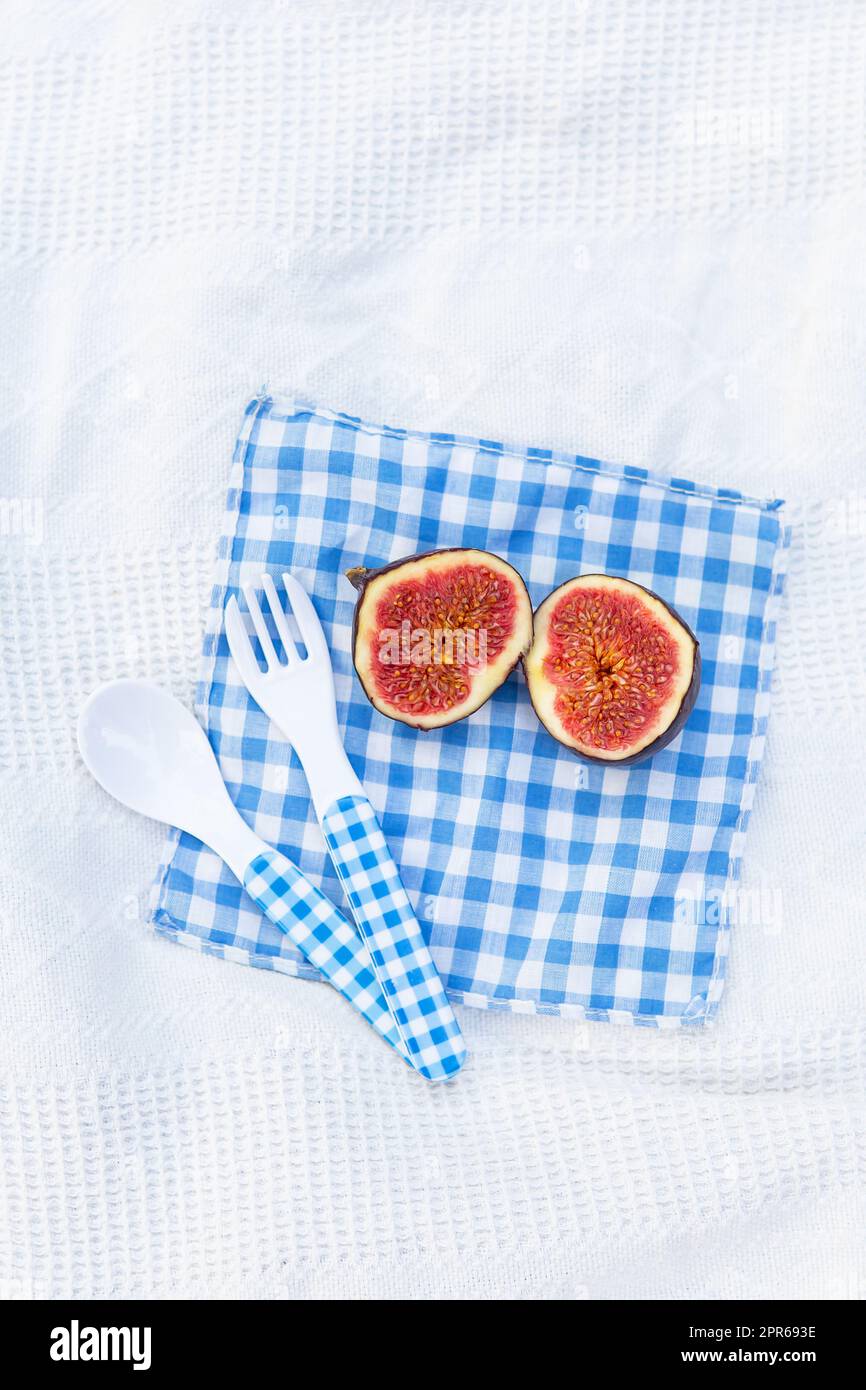 Frische, biologisch reife Feigen, in zwei Teile geschnitten, liegen auf einer blauen karierten Serviette. Feigen für die Konfitüre vorbereiten. Herbstgericht. Geben Sie Platz für Text frei. Stockfoto