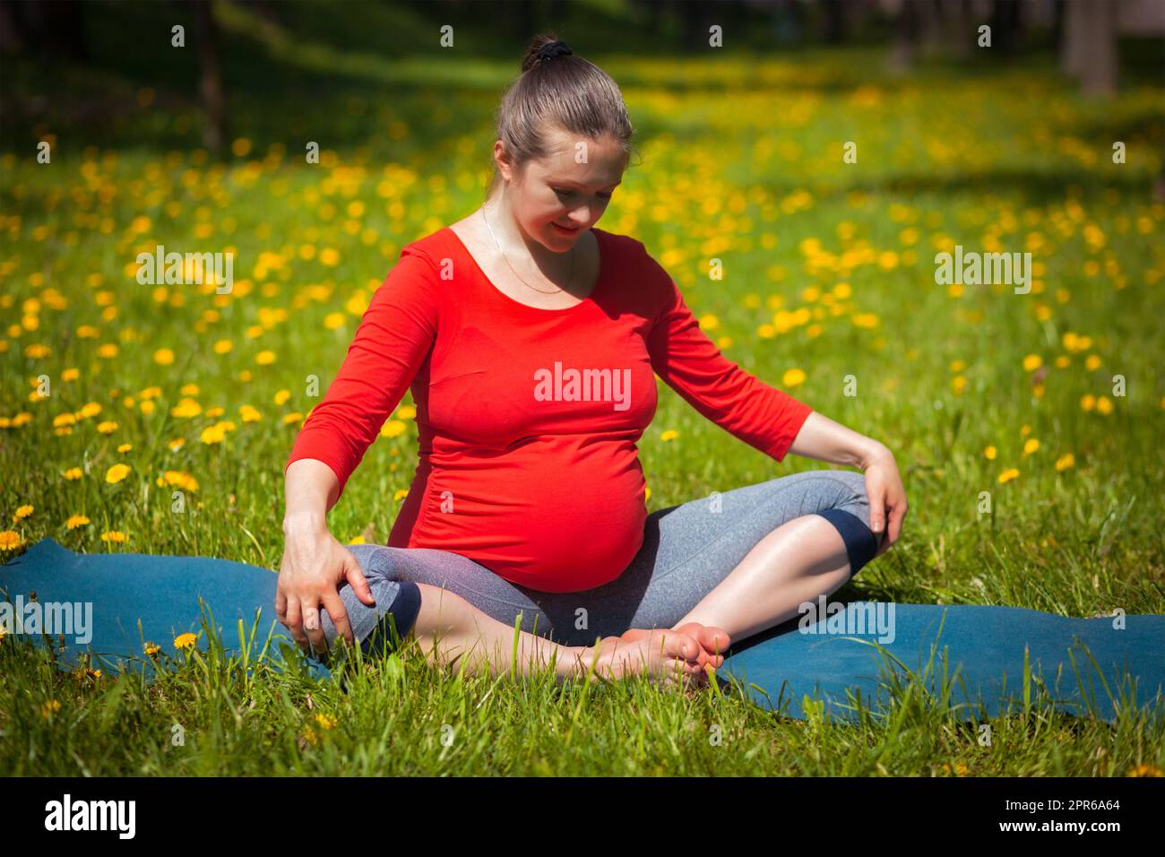Schwanger Frau tun Asana baddha konasana im Freien Stockfoto