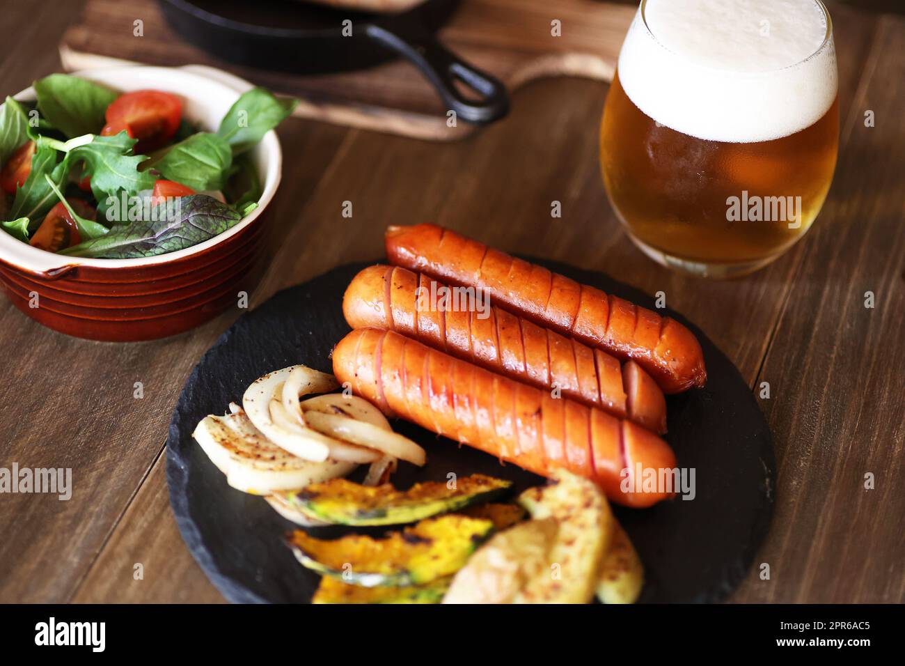 Würstchen und gegrilltes Gemüse mit einem Glas Bier Stockfoto