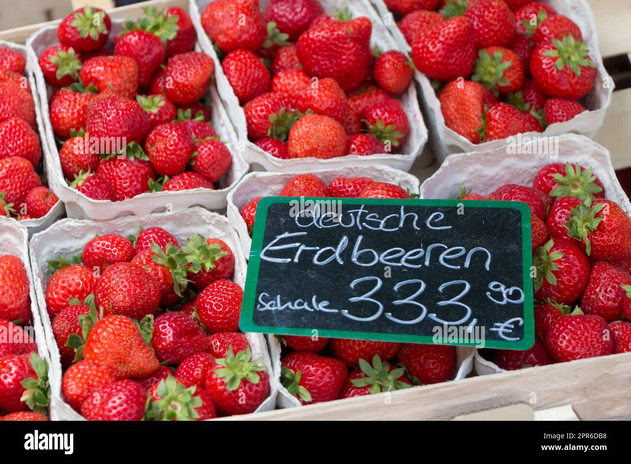 Tassen mit frischen, süßen Erdbeeren auf dem Marktplatz. Lokaler Bioobstverkauf mit deutschem Euro-Preisschild zur Inflationszeit in deutschland. Stockfoto