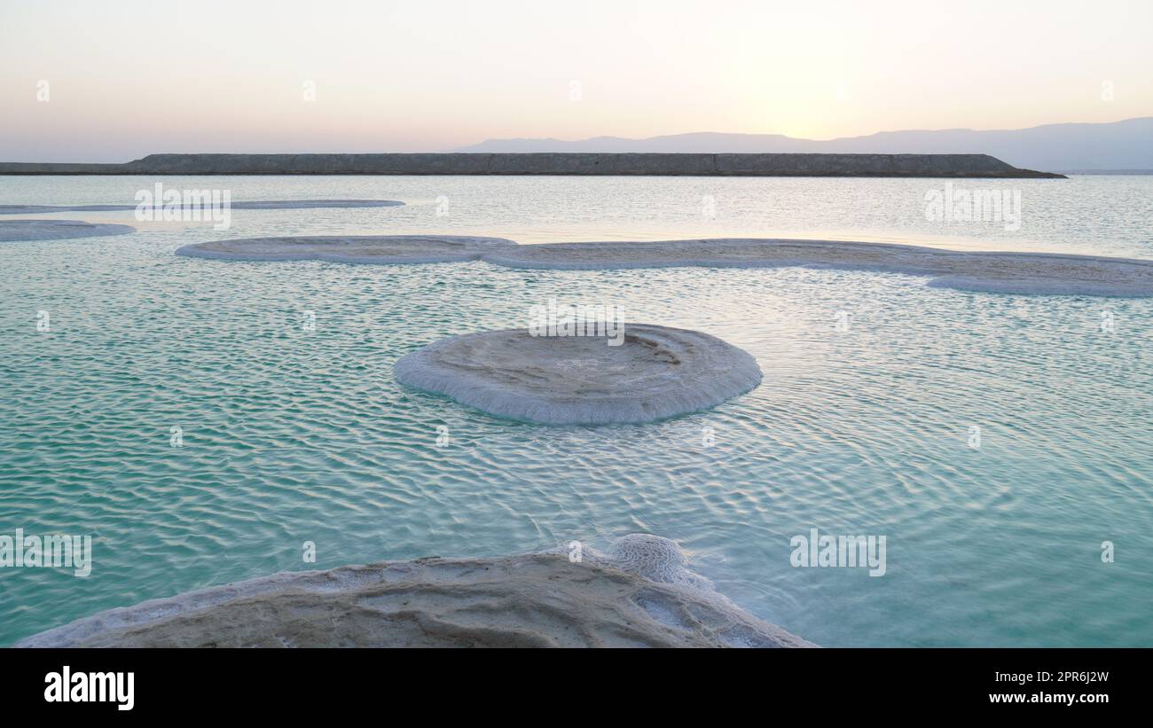 Großes Salz sammelte sich am Ufer des Toten Meeres. Ablagerungen von Mineralsalzen, typische Landschaft des Toten Meeres. Salz am Strand bei Sonnenaufgang. Stockfoto