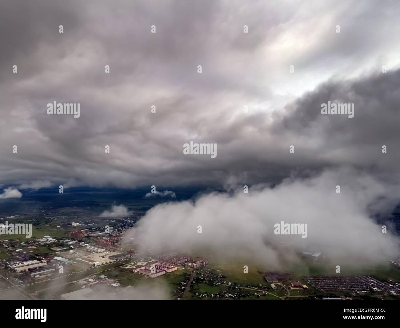 Fliegen durch dicke Wolken. Regenwolken am Himmel. Kumuluswolken, Meteorologie und Klimastudien. Foto der Stadt aus der Höhe der Wolken, Luftaufnahmen. Quadcopter, Drohne Stockfoto