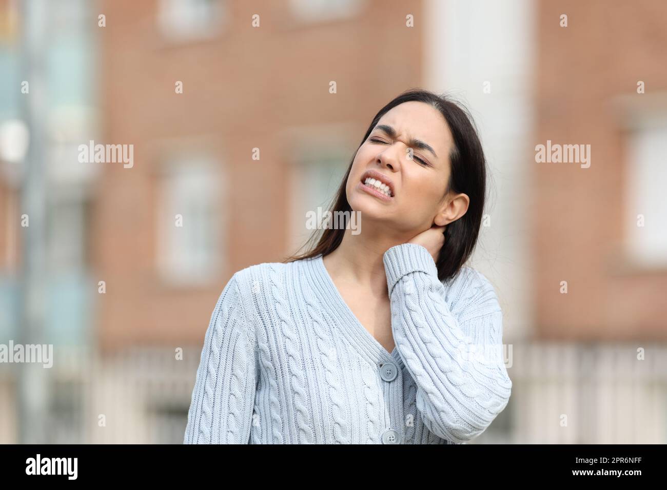 Eine gestresste Frau leidet unter Nackenschmerzen und klagt allein Stockfoto