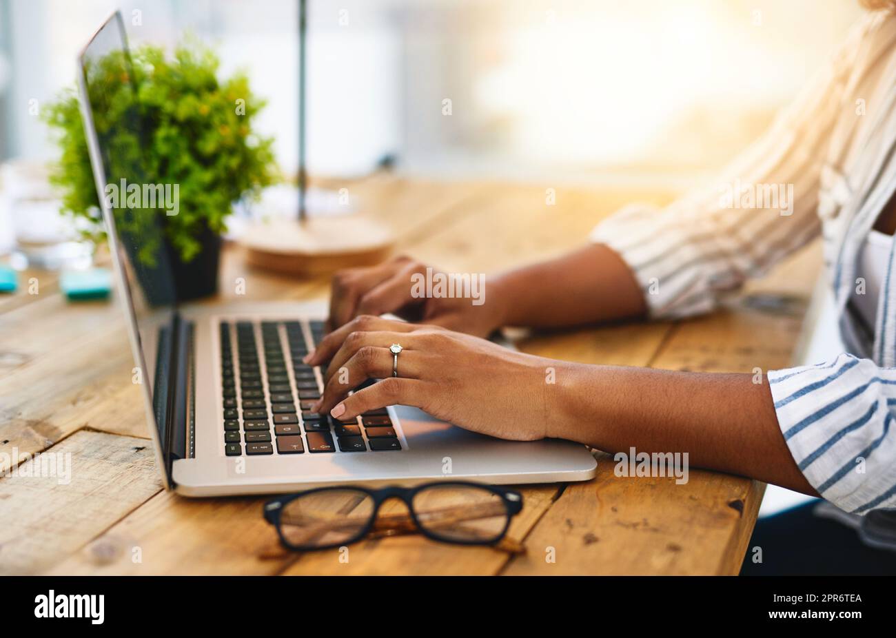 Sei mutig, sei kreativ. Ausgeschnittene Aufnahme einer Frau, die ihren Laptop auf einem Holztisch benutzt. Stockfoto