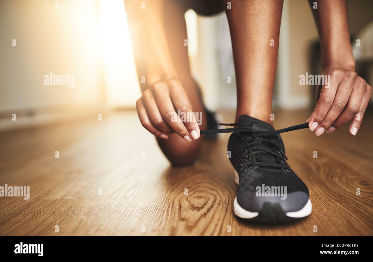 Lauf den Tag oder es läuft dich. Kurzer Schuss einer jungen Frau, die ihre Schnürsenkel bindet. Stockfoto