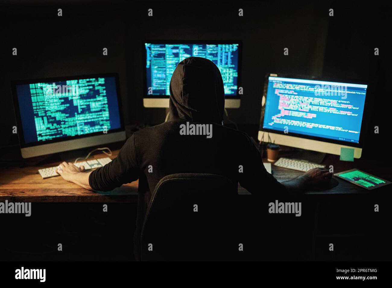 Entwirren des Codes. Rückansicht eines jungen Hackers, der im Dunkeln einen Computercode knackt. Stockfoto