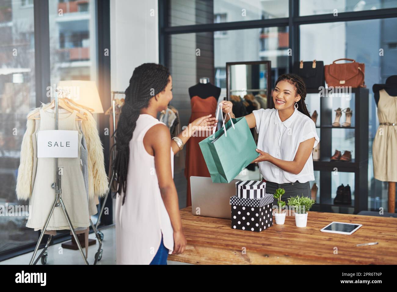 Im Zweifelsfall einkaufen. Eine kleine Aufnahme eines jungen Ladenbesitzers, der einem Kunden ein Paket über den Ladentisch übergab. Stockfoto