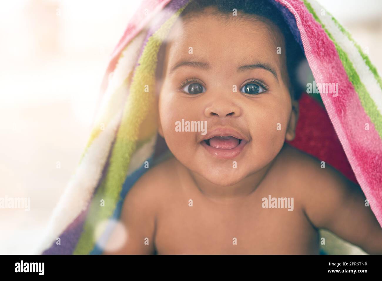 Babys machen die Welt zu einem süßeren Ort. Aufnahme eines entzückenden kleinen Mädchens, das in einer bunten Decke zu Hause bedeckt ist. Stockfoto