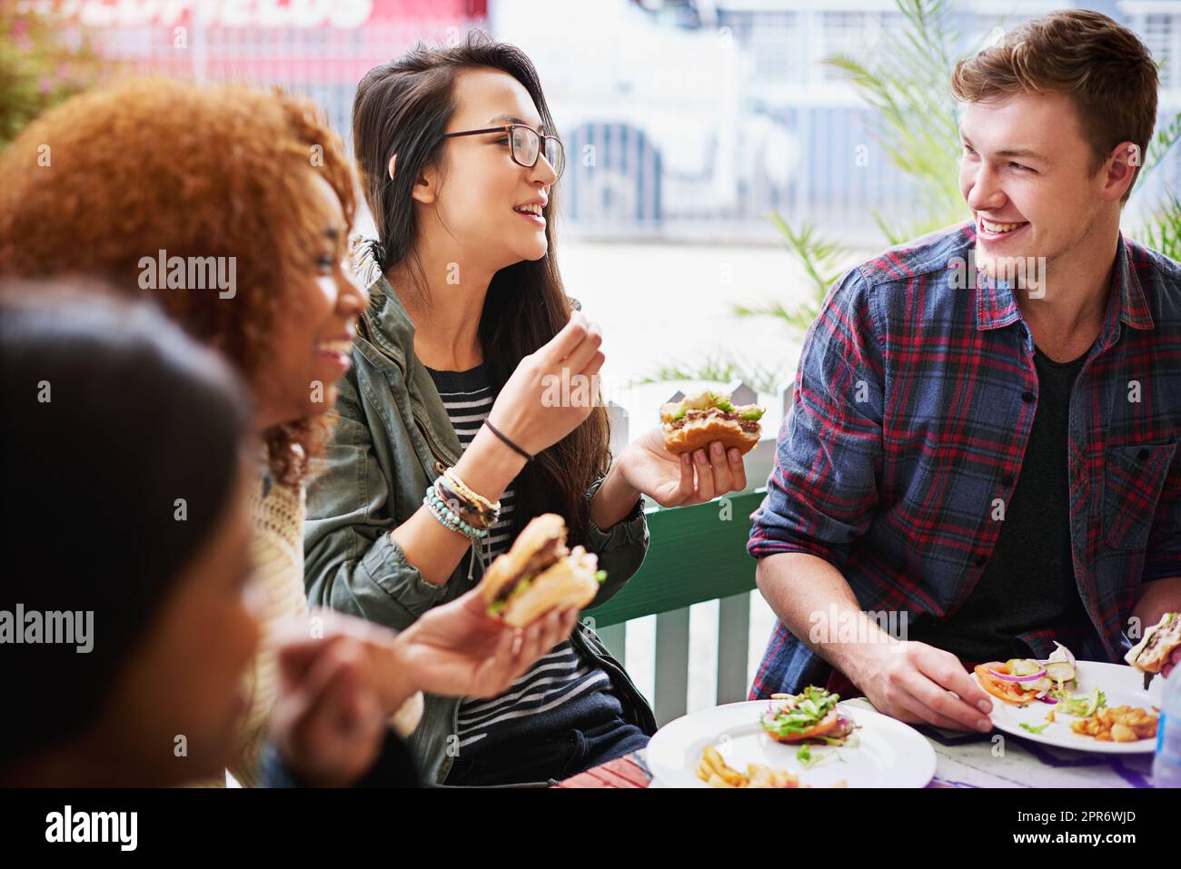 Fastfood und Freundschaft. Eine kurze Aufnahme einer Gruppe von Freunden, die im Freien Burger essen. Stockfoto