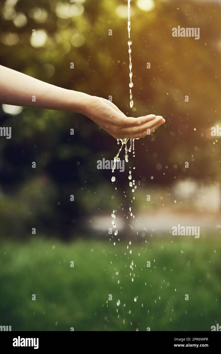 Wasser ist die treibende Kraft aller Natur. Ein kurzer Wasserschuss, der auf einer Frauenhand draußen läuft. Stockfoto