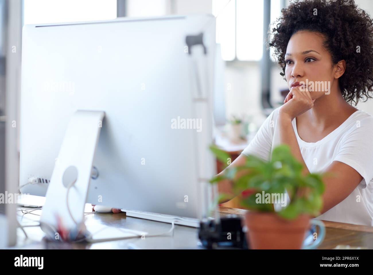Tief in Prozesse zur Lösungssuche eingebunden. Selbstbewusste Frau, die an ihrem Schreibtisch in einem offenen Bürobereich arbeitet. Stockfoto