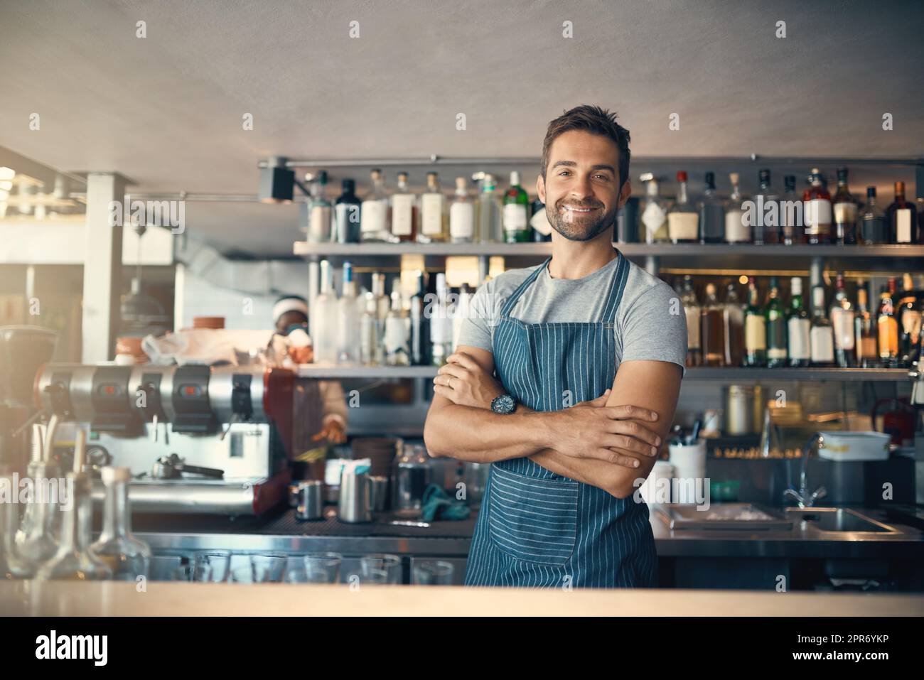 Es gibt einen Grund, warum meine Kunden immer wieder kommen. Porträt eines jungen Mannes, der hinter einer Theke arbeitet. Stockfoto