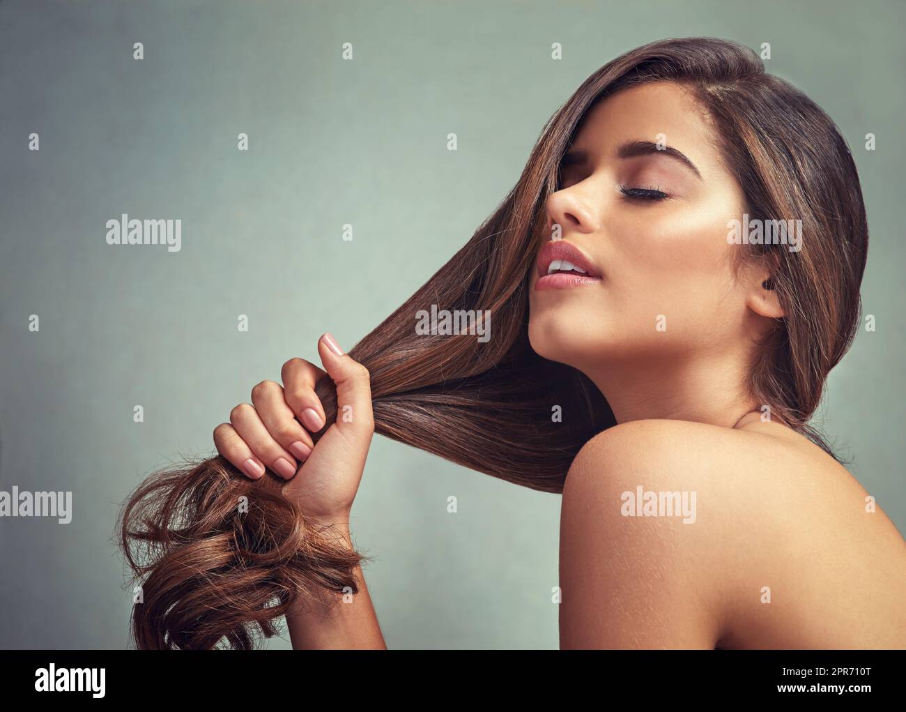 Liebe dich selbst, liebe dein Haar. Studioaufnahme einer schönen Frau mit langen Schlössern, die vor einem grauen Hintergrund posiert. Stockfoto