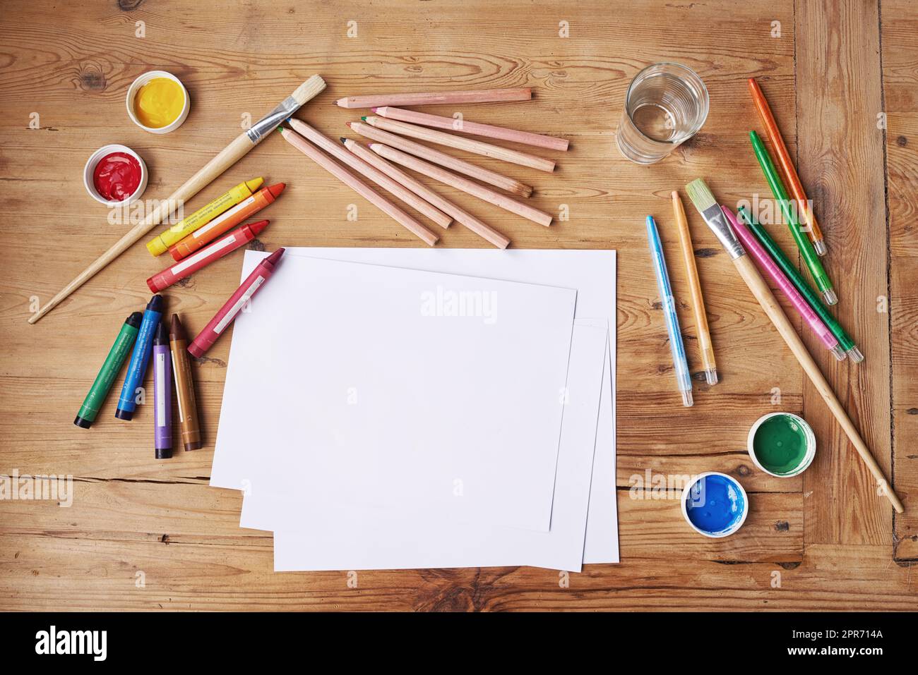 Kreativität braucht Mut. Leeres Papier mit Malutensilien und Bleistiften auf einem Holztisch. Stockfoto