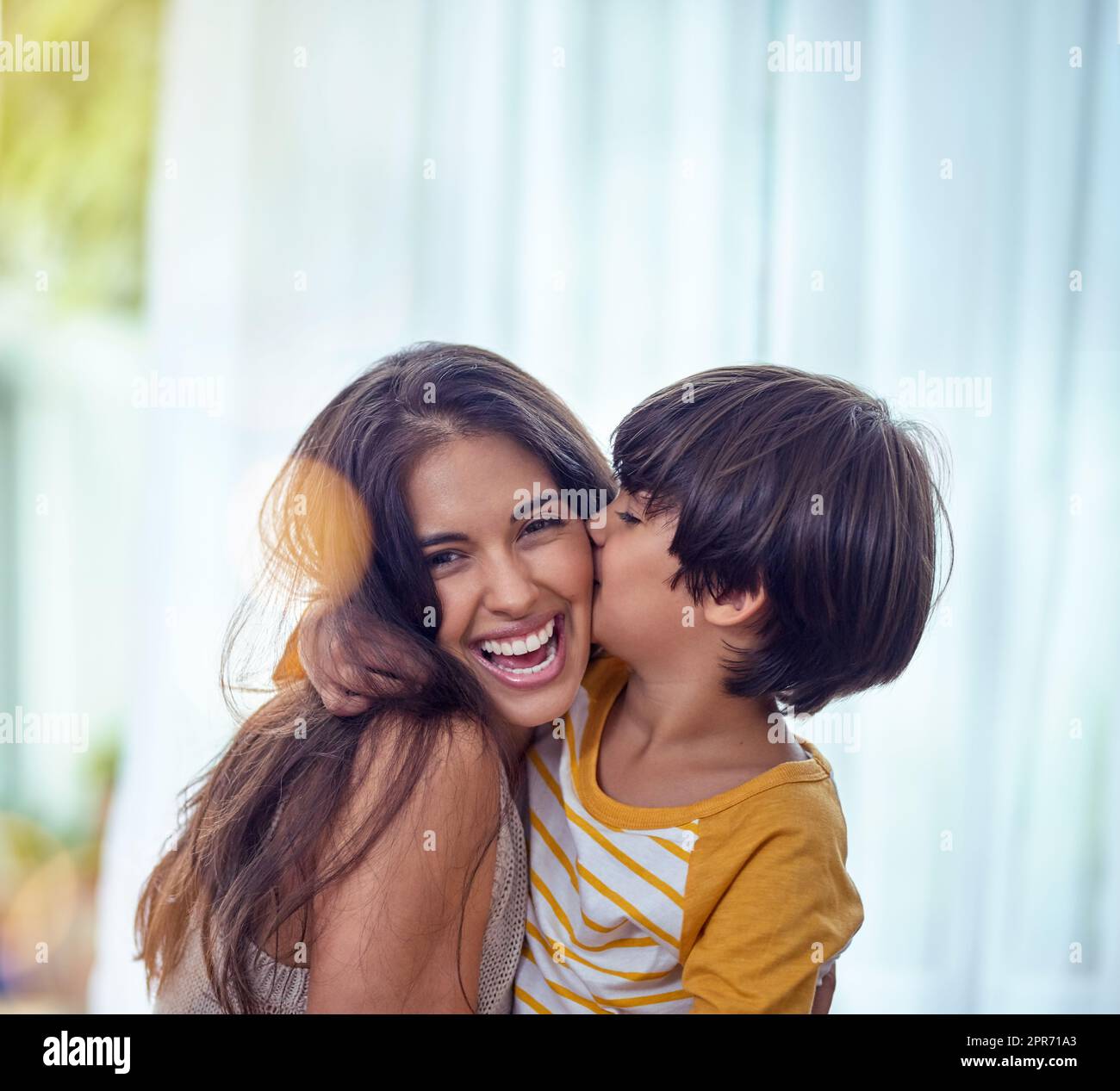 Glücklich ist das Kind, dessen Mutter glücklich ist. Aufnahme eines entzückenden kleinen Jungen, der seine Mutter zu Hause liebevoll küsst. Stockfoto