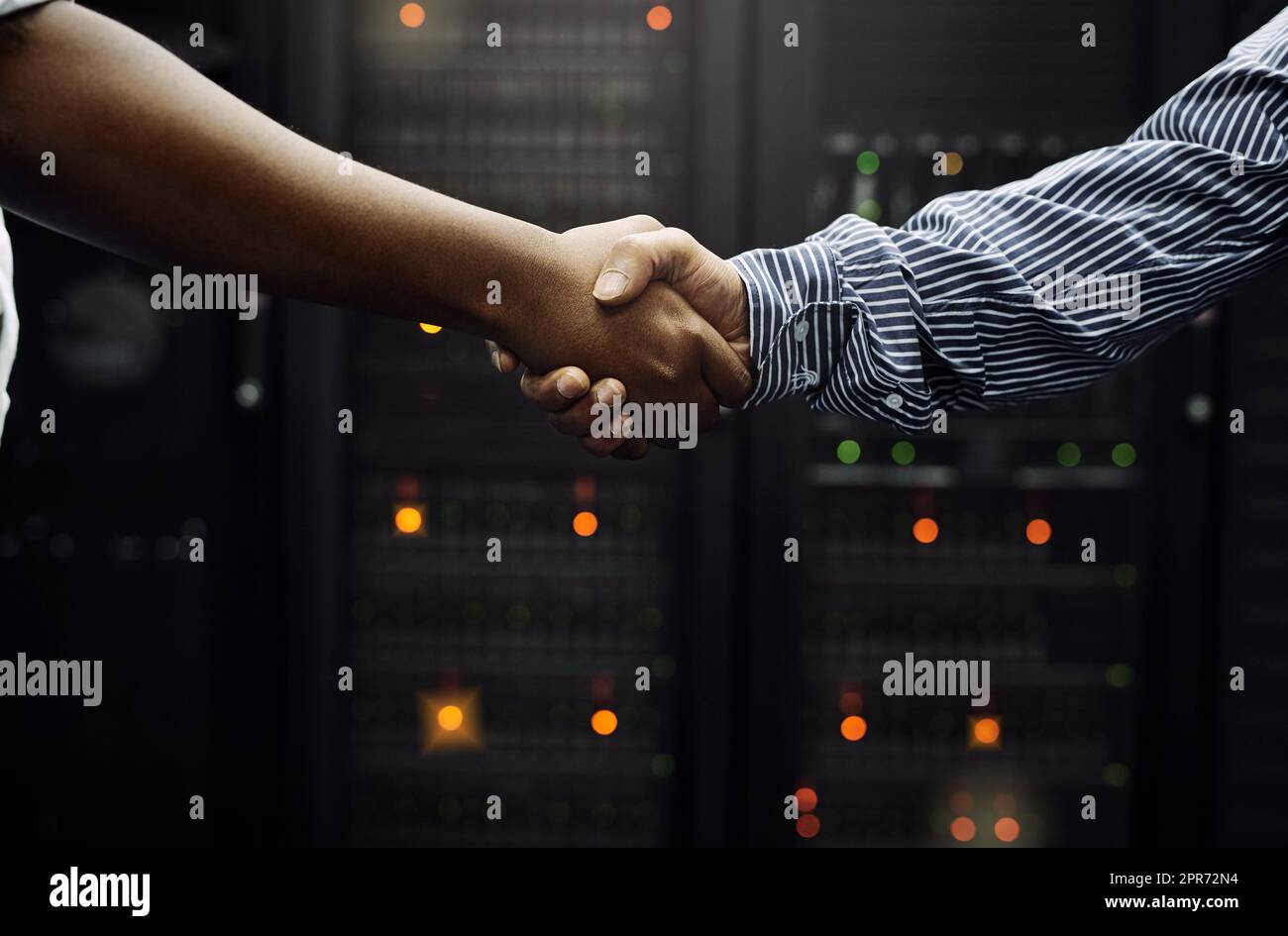 Gepaart für professionellen IT-Service. Eine kurze Aufnahme von zwei unkenntlichen Männern, die sich vor einem Server in einem Rechenzentrum die Hände schüttelten. Stockfoto
