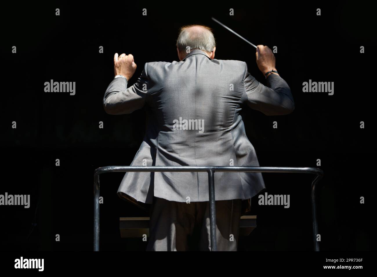 Führung der Musik. Beschnittene Rückansicht eines Orchesterdirigenten, der seinen Taktstock winkt. Stockfoto