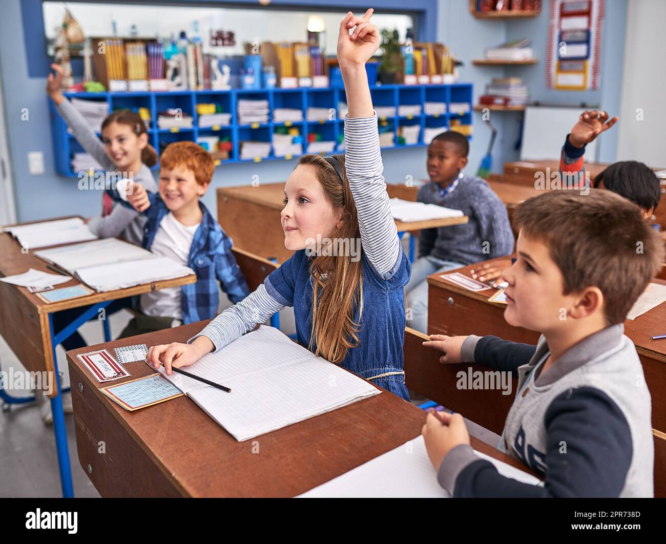 Alle wollen die Frage beantworten. Eine kleine Aufnahme von Grundschulkindern in der Klasse. Stockfoto