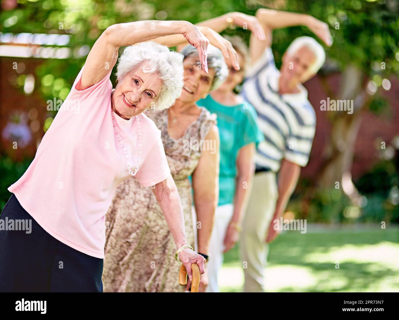 Aktiv zu bleiben ist der Schlüssel zu einem gesunden Ruhestand. Aufnahme einer Gruppe lächelnder Senioren, die draußen trainieren. Stockfoto