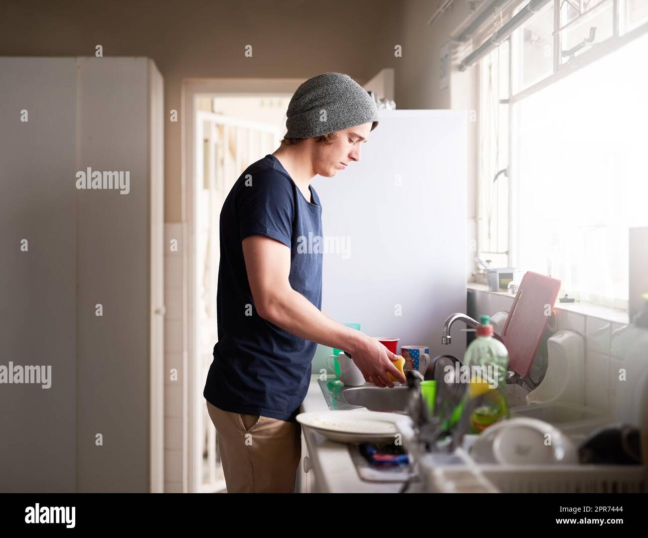 Seine Küche sauber halten. Eine kurze Aufnahme eines jungen Mannes, der zu Hause die Gerichte macht. Stockfoto