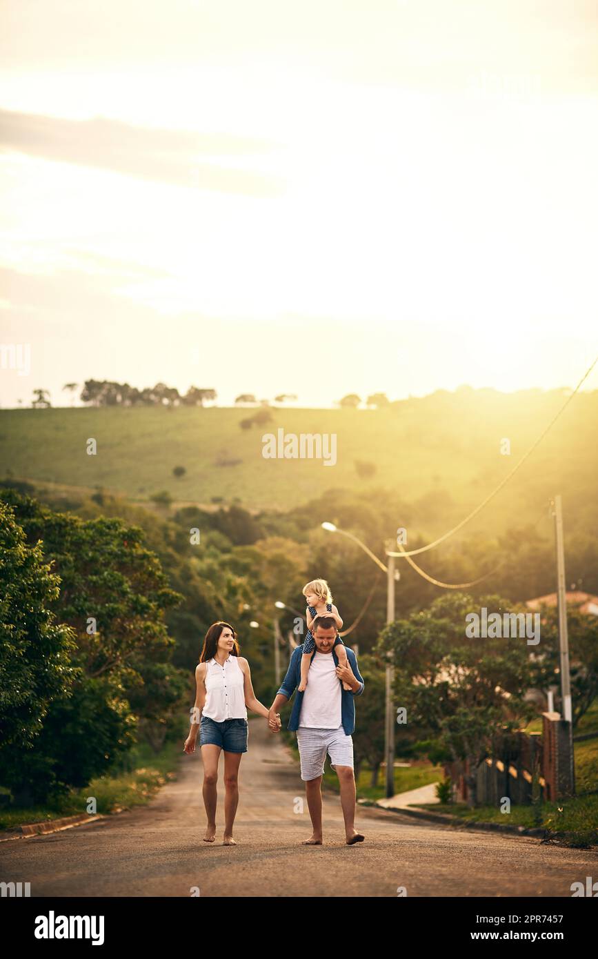 Genießen Sie die einfachen Dinge mit denen, die Sie lieben. Aufnahme einer jungen Familie, die draußen die Straße entlang spazieren geht. Stockfoto