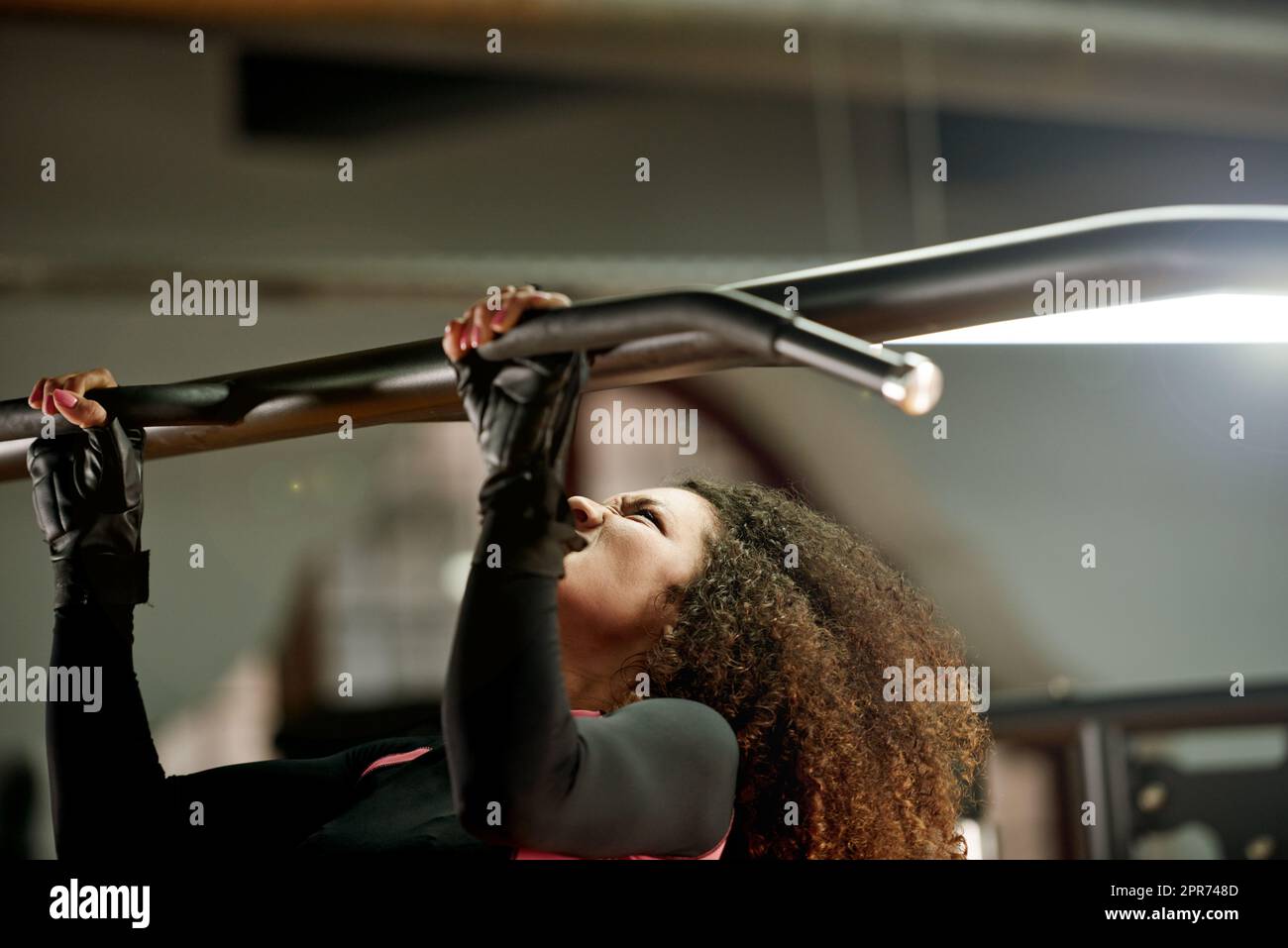 Stark ist die einzige Option. Aufnahme einer jungen Frau, die im Fitnessstudio Pull-ups macht. Stockfoto