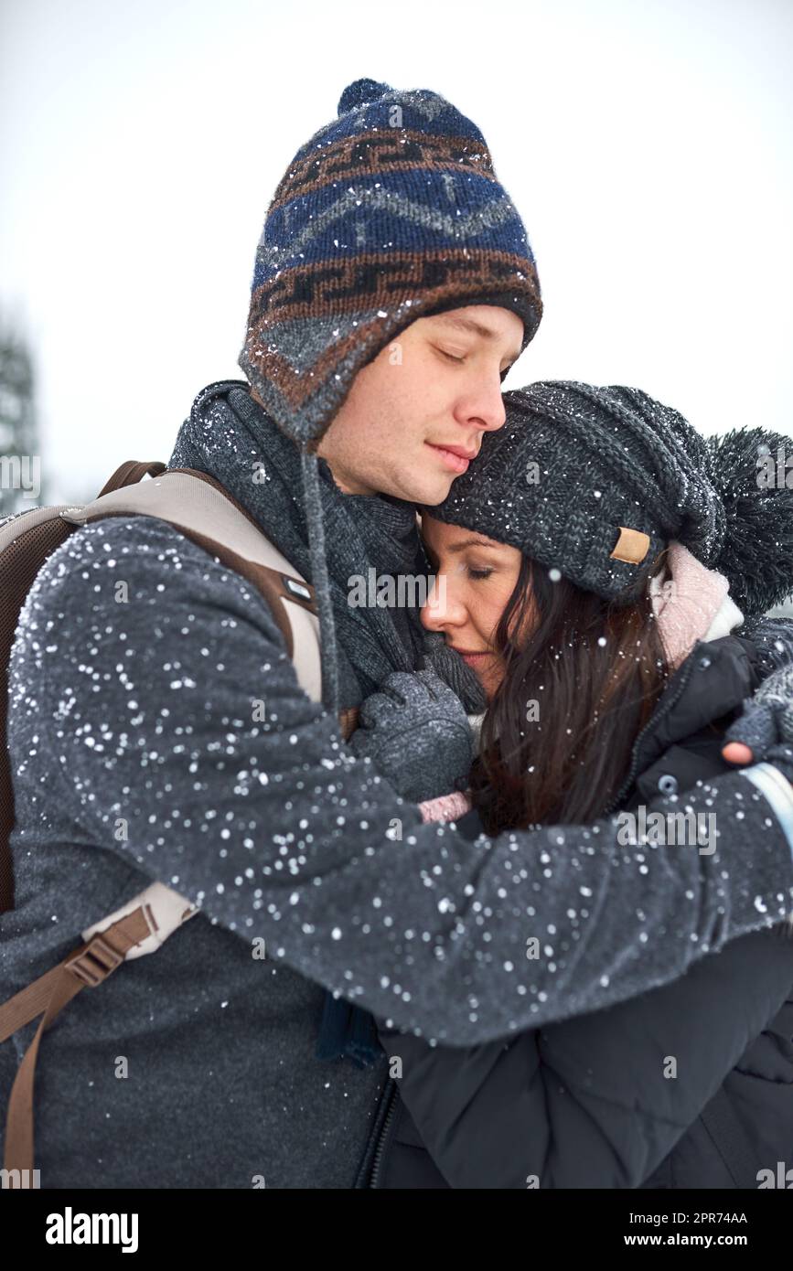 Ich halte dich warm. Aufnahme eines glücklichen jungen Paares, das sich beim draußen im Schnee amüsieren kann. Stockfoto