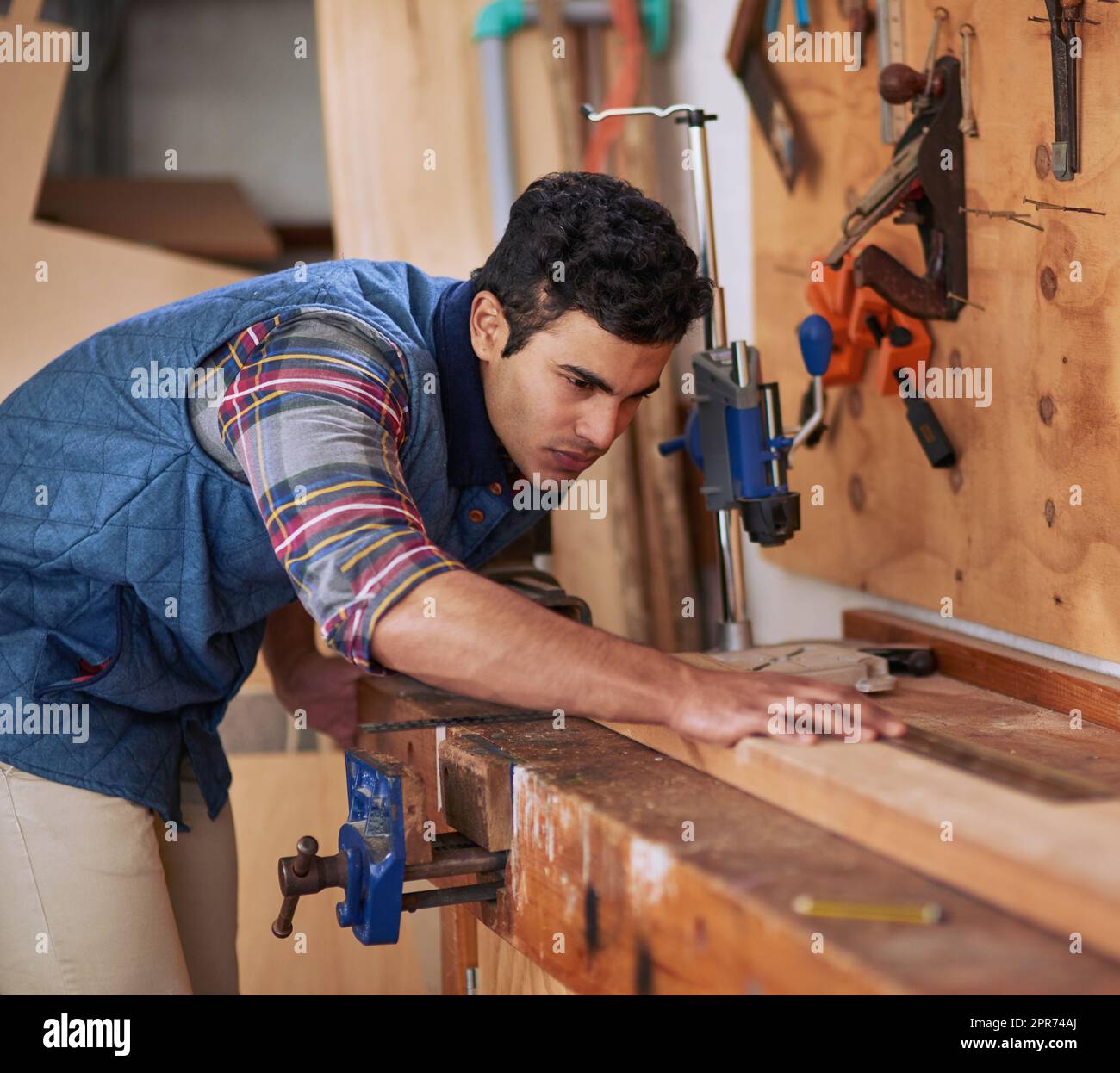Details machen den Unterschied. Aufnahme eines fokussierten Handwerkers, der während der Arbeit in seiner Werkstatt ein Stück Holz misst. Stockfoto