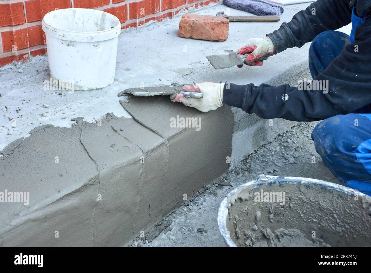 Ein Arbeiter verwendet einen Spachtel, um das Zementgemisch entlang der Rampe zu verteilen Stockfoto