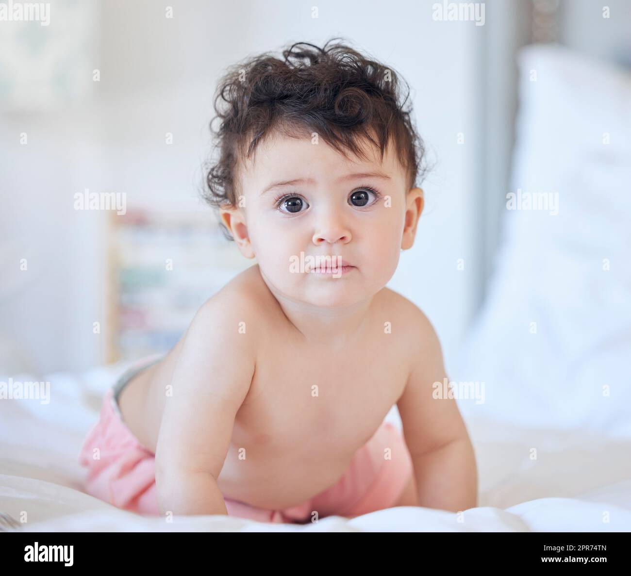 Ein kaukasisches Mädchen, das am Tag oder Morgen alleine auf dem Bett zu Hause spielt und auf das Konzept der Kindheit und des Heranwachsens der Kamera schaut Stockfoto