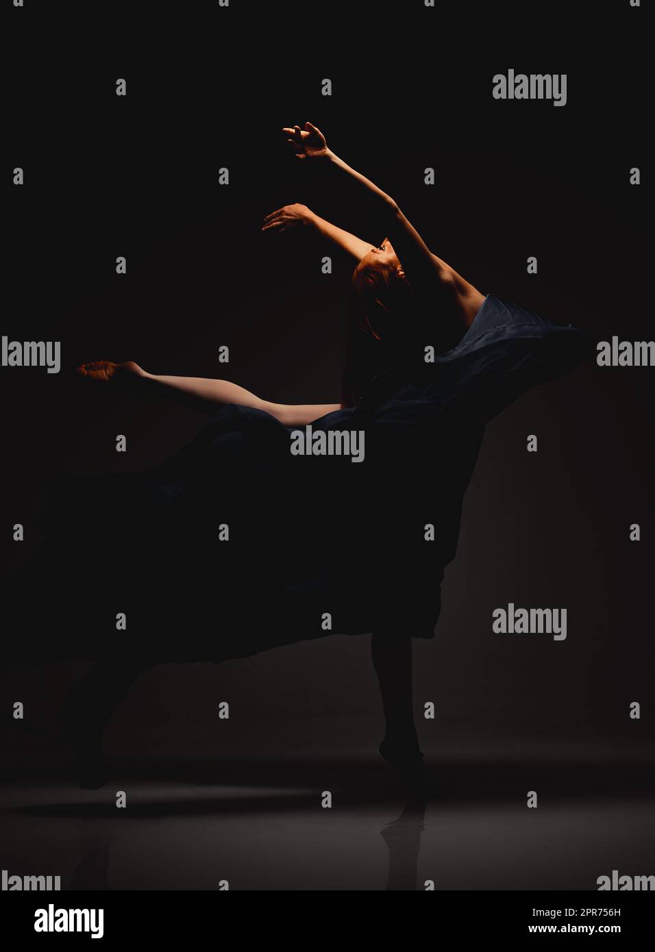 Erleben Sie ihre makellosen Bewegungen. Aufnahme eines Darstellers, der vor dunklem Hintergrund tanzt. Stockfoto
