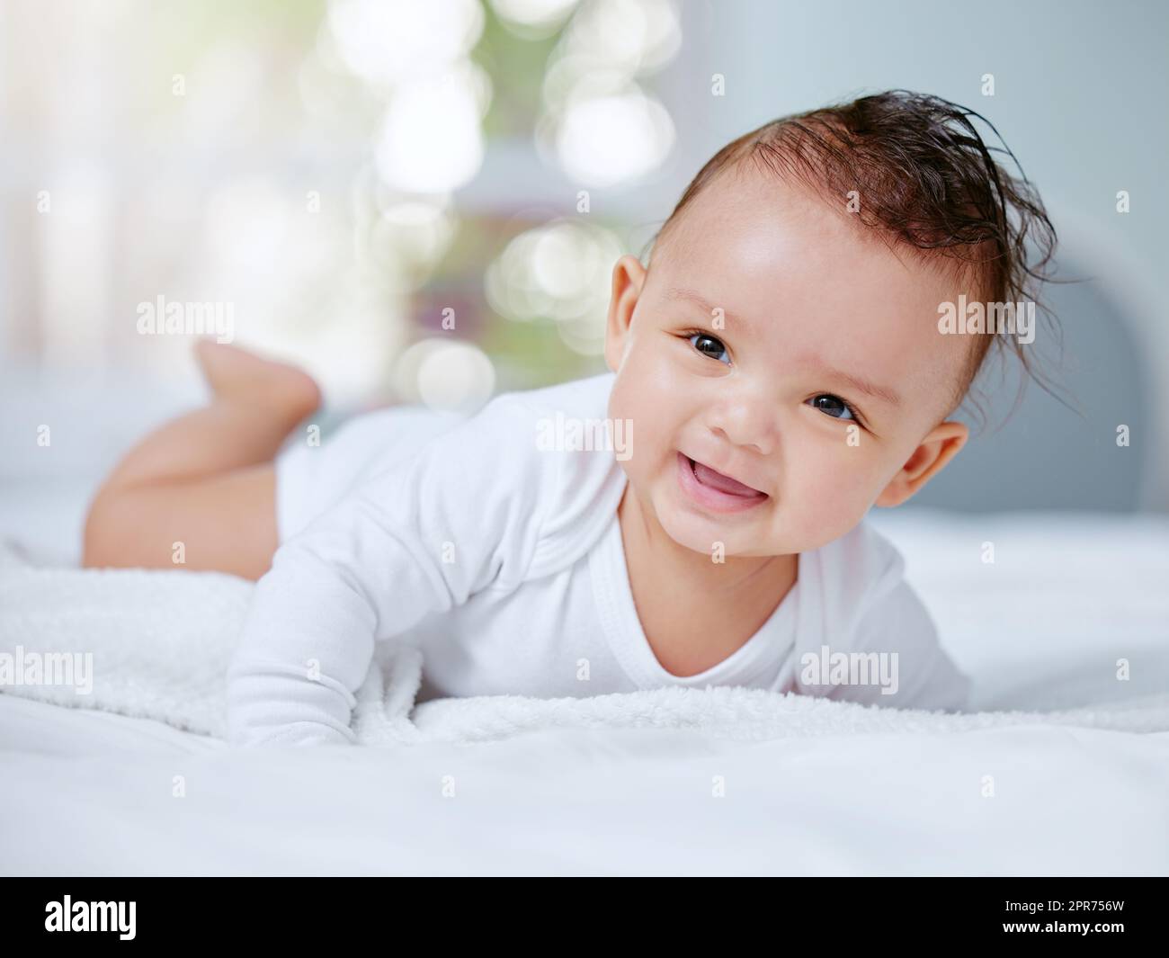 Spielzeit ist für die Entwicklung von entscheidender Bedeutung. Aufnahme eines kleinen Babys, das auf ihrem Bett spielt. Stockfoto