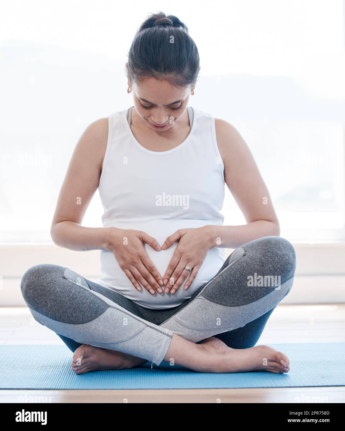 Ich hätte euch nicht mehr lieben können. Aufnahme einer Schwangeren, die zu Hause Yoga macht. Stockfoto