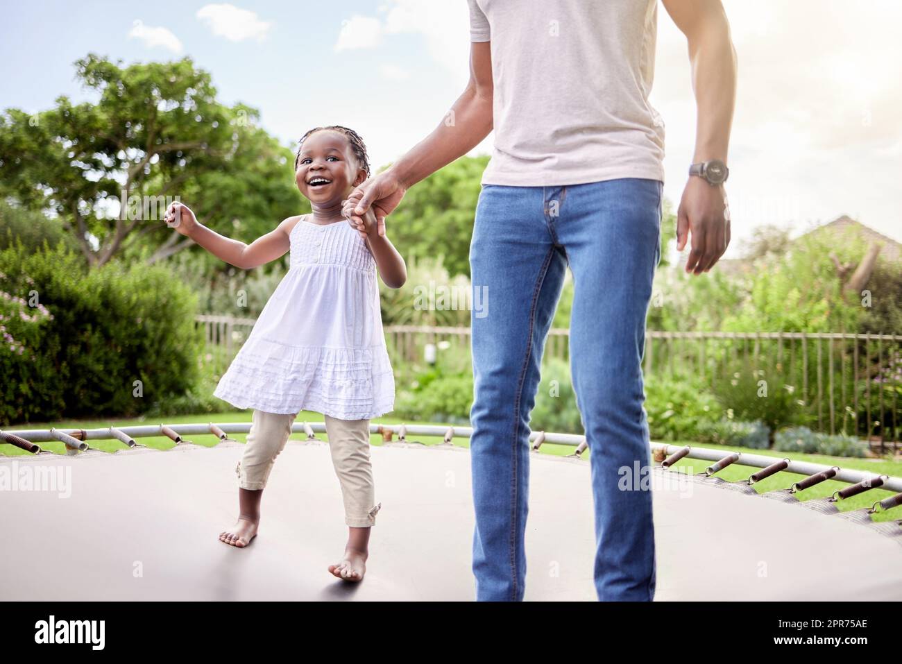 Ich halte dich nicht in der Hand, damit du hoch springen kannst. Aufnahme eines kleinen Mädchens, das mit ihrem Vater im Freien auf einem Trampolin springt. Stockfoto