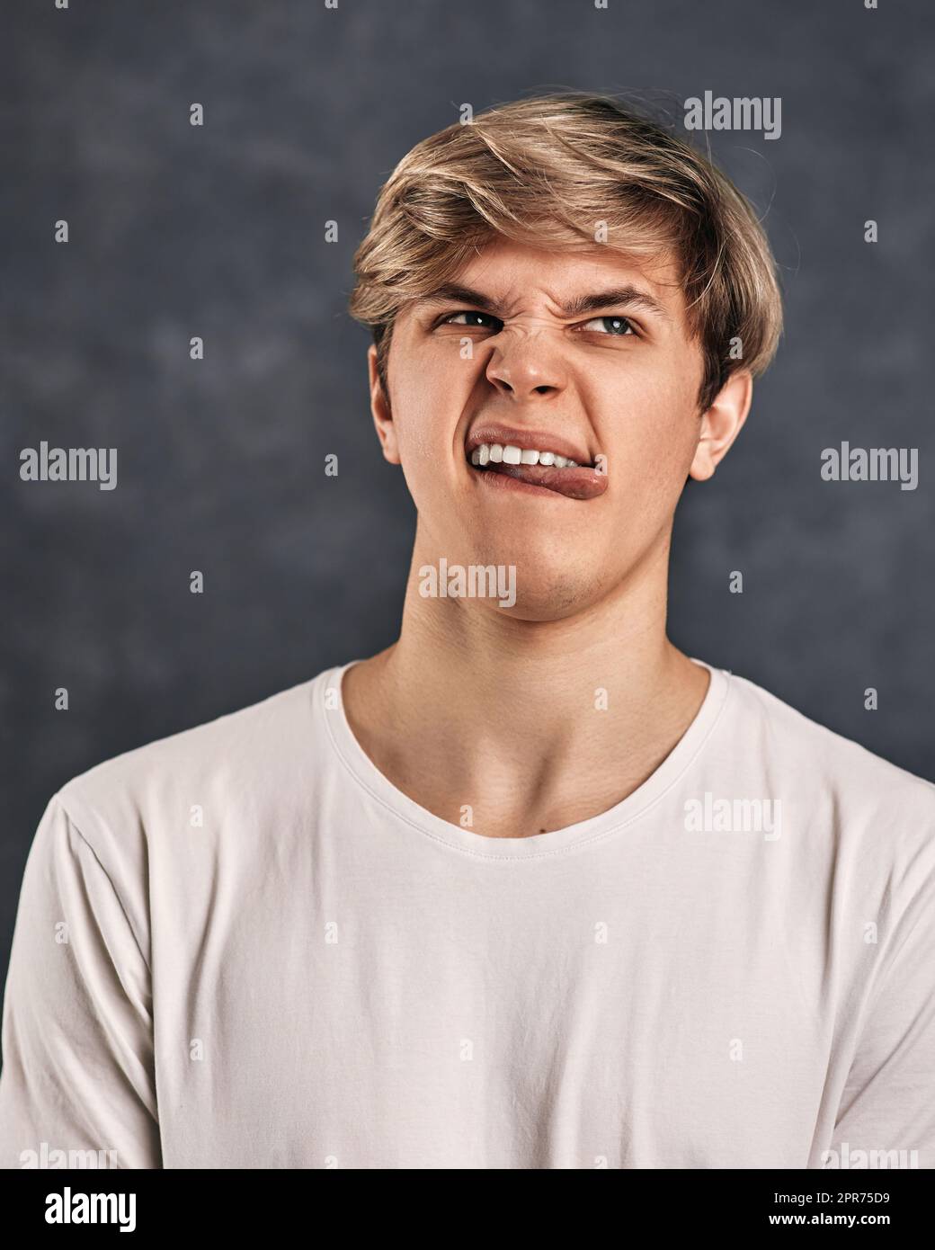 Junger Mann, der Negativität auf grauem Hintergrund ausdrückt. Stockfoto