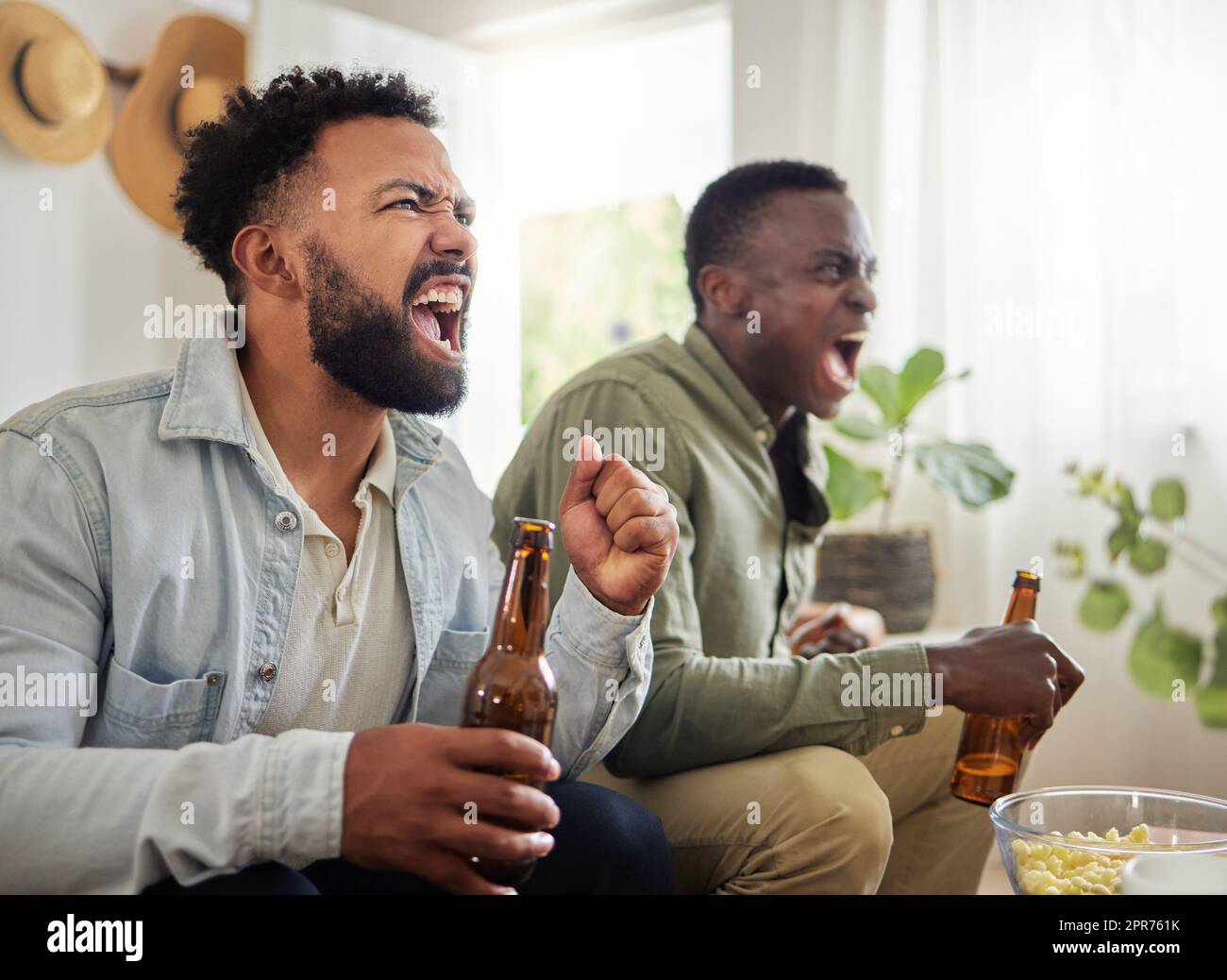 Haben dieses hier gewonnen. Aufnahme von zwei männlichen Freunden, die beim Bieren und Beisitzen fröhlich aussehen. Stockfoto