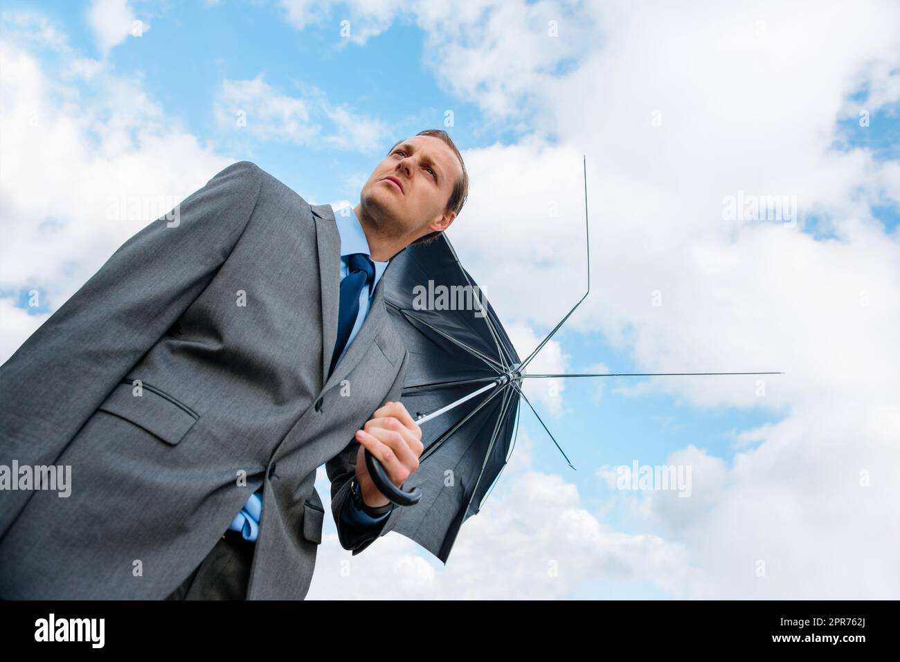 Keine Deckung für ihn in Sicht. Aufnahme eines Geschäftsmanns, der einen zerbrochenen Regenschirm in der Hand hält. Stockfoto