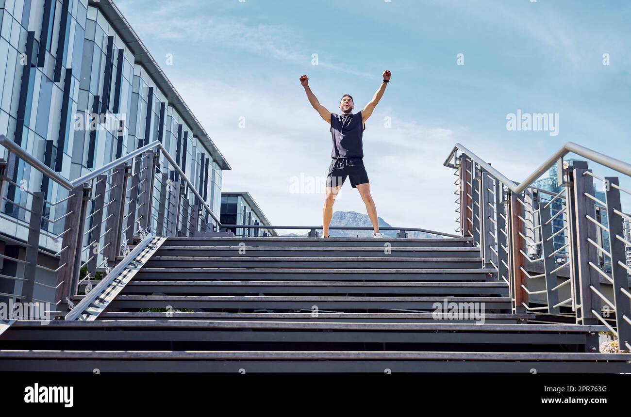 Der erste Platz gehört mir. Aufnahme eines sportlichen jungen Mannes, der oben auf einer Treppe jubelt, während er im Freien trainiert. Stockfoto