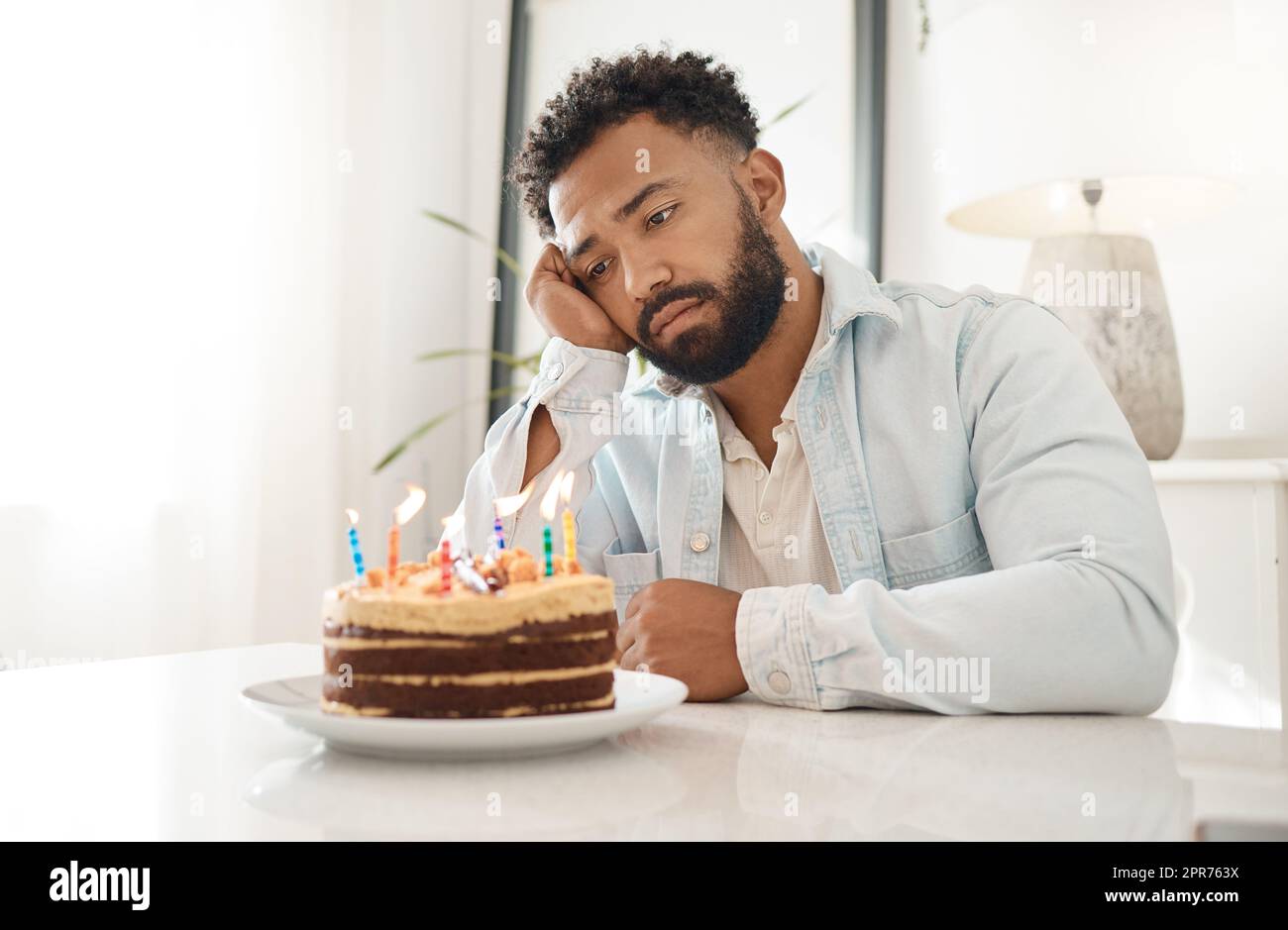Wenn niemand zu deinem Geburtstag aufkommt. Aufnahme eines jungen Mannes, der zu Hause seinen Geburtstag allein feiert. Stockfoto