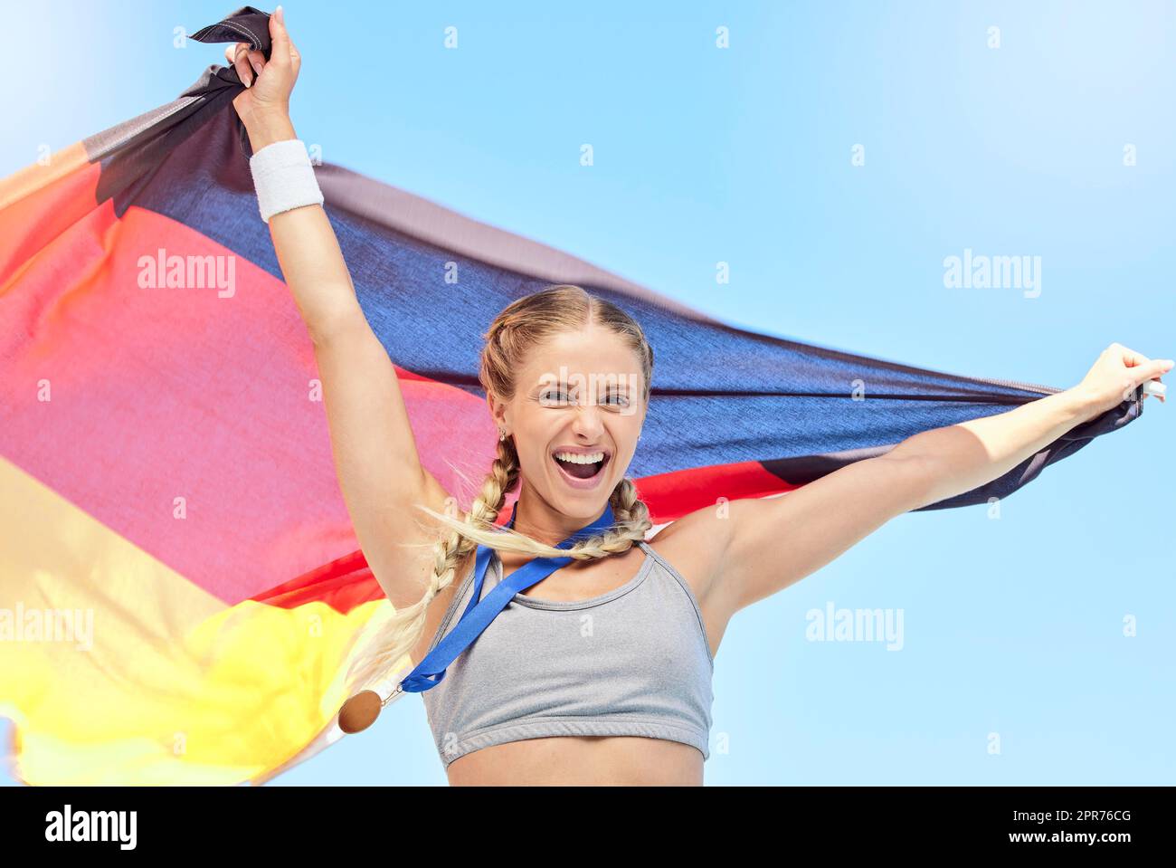 Portrait des erfolgreichen Athleten, der nach einem Sportwettbewerb die deutsche Flagge hielt. Lächelnde Passform aktiv sportlich motivierte Frau. Wir feiern mit Nationalstolz, dass wir im olympischen Sport eine Goldmedaille erhalten haben Stockfoto