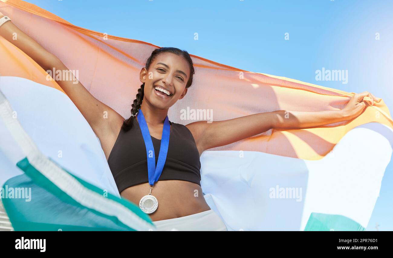 Porträt einer jungen, fit gewordenen indischen Sportlerin, die nach einem Wettkampf im Sport jubelt und die indische Flagge hält. Ein Lächeln passt sich einer sportlichen, aktiven Frau an, die motiviert ist und feiert Stockfoto