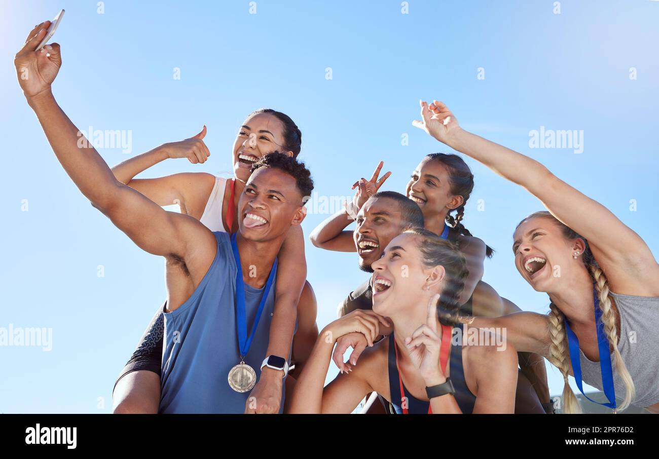 Eine Gruppe verschiedener olympiasieger macht ein Selfie, während sie Spaß haben und Handgesten zeigen. Glückliche und fröhliche Läufer machen gemeinsam ein Foto. Junger männlicher Sprinter macht ein Foto mit Sportlern Stockfoto