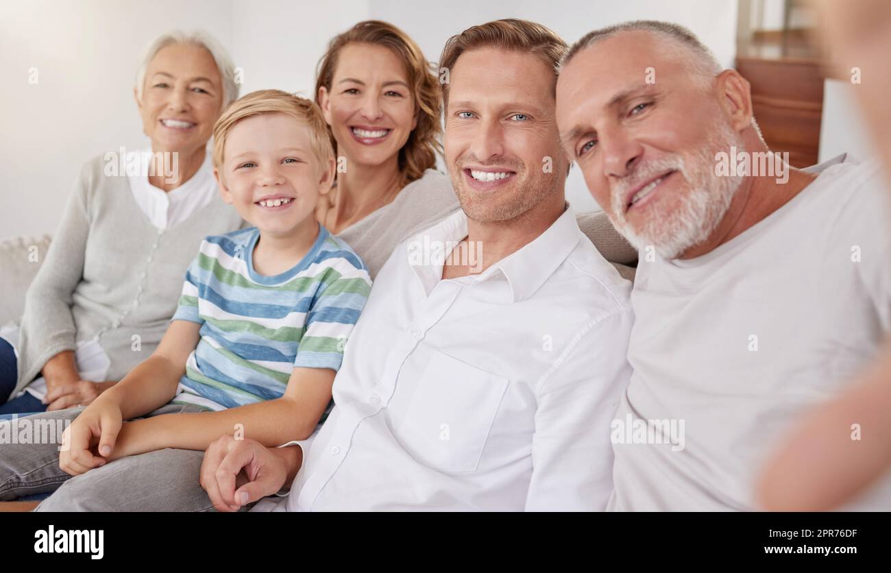 Porträt einer glücklichen, weißhäutigen Familie, die zu Hause Selfies macht. Der kleine Junge entspannt sich und verbindet sich mit sorglosen Eltern und Großeltern, während er Fotos und Bilder für besondere Erinnerungen aufnimmt Stockfoto