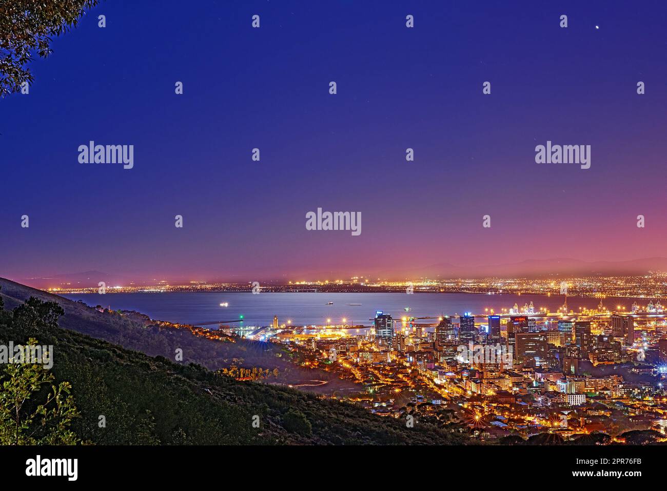 Signal Hill in Kapstadt, Südafrika mit Copyspace vor dunklem Nachthimmel Hintergrund und Blick auf eine Küstenstadt. Malerische Panoramalandschaft aus Lichtern, die eine urbane Skyline entlang des Meeres erleuchten Stockfoto
