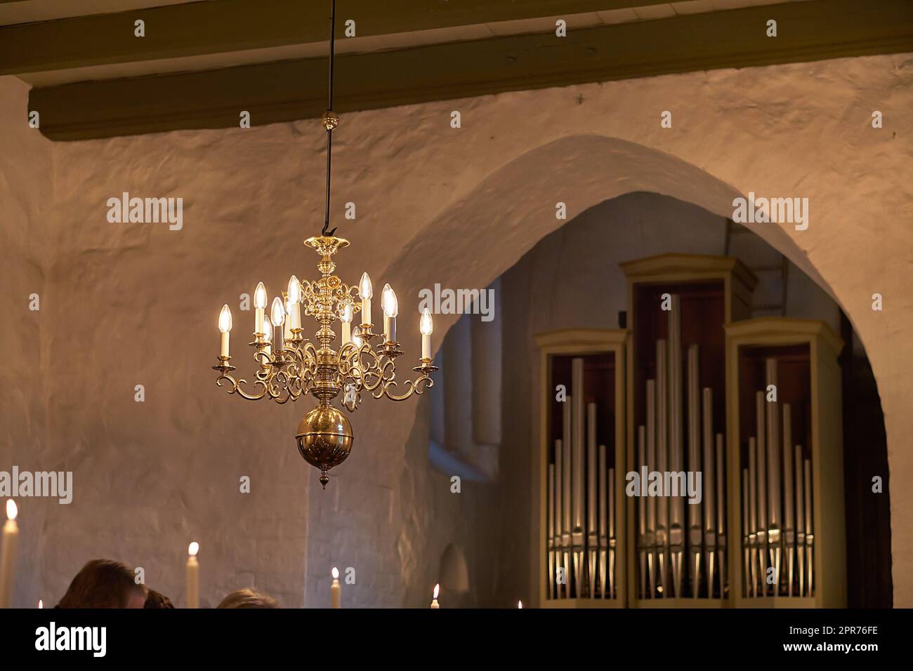 Altmodischer Messingkronleuchter mit Kerzenlampen, die vom Dach oder von der Decke hängen, in einem historischen Gebäude und einem alten Raum. Glänzende dekorative, mittelalterliche, antike und antike Leuchten in einem Herrenhaus Stockfoto