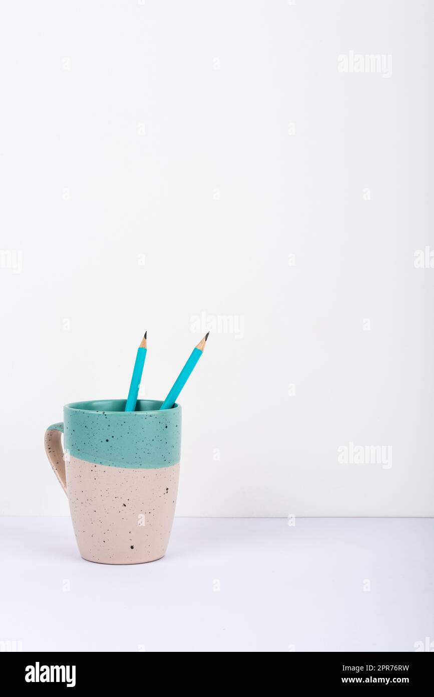 Tasse Mit Zwei Bleistiften Innen Auf Dem Schreibtisch Platziert. Becher Mit Stifte Auf Dem Tisch. Fall Mit Darin Eingeschritzener Schrift. Gehäuse Mit Büromaterial. Stockfoto