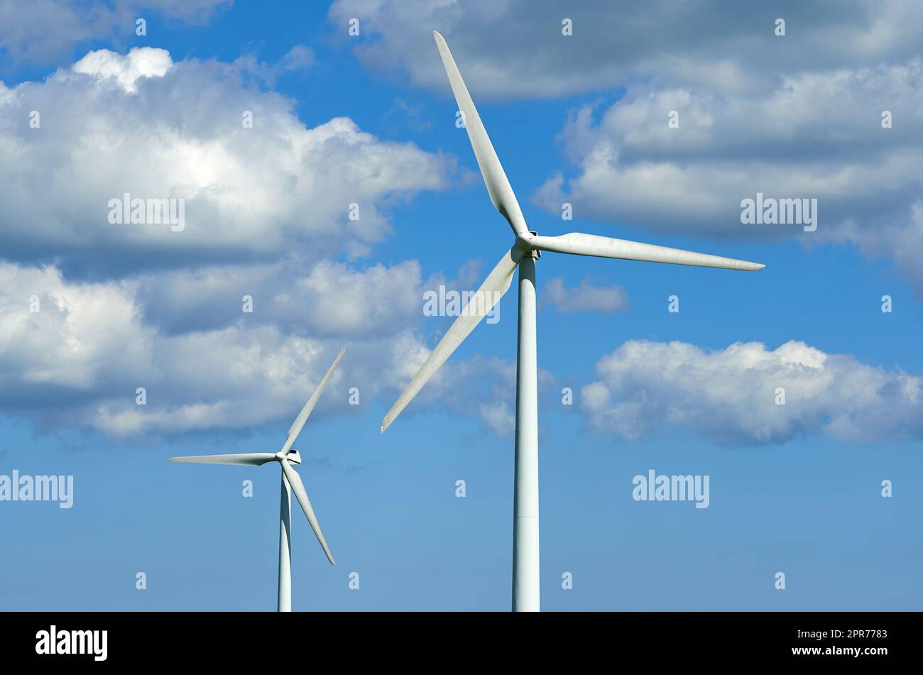 Windturbinen und Umweltinfrastruktur isoliert gegen den blauen Himmel mit Kopierraum auf einem leeren Energiefarm. Propeller, die nachhaltige Energie in elektrische Energie in abgelegenen und ländlichen Gebieten umwandeln Stockfoto
