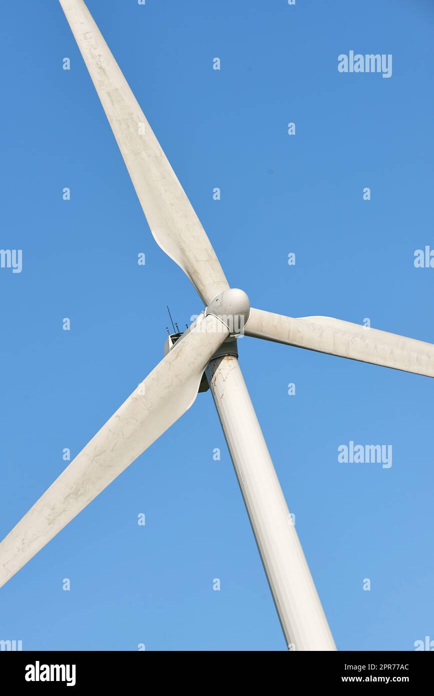 Nahaufnahme einer Windturbine und von Propellorblättern vor einem blauen Himmelshintergrund von unten. Nutzung einer nachhaltigen und erneuerbaren Energiequelle zur Erzeugung von Strom und Strom aus windigen Klimazonen Stockfoto