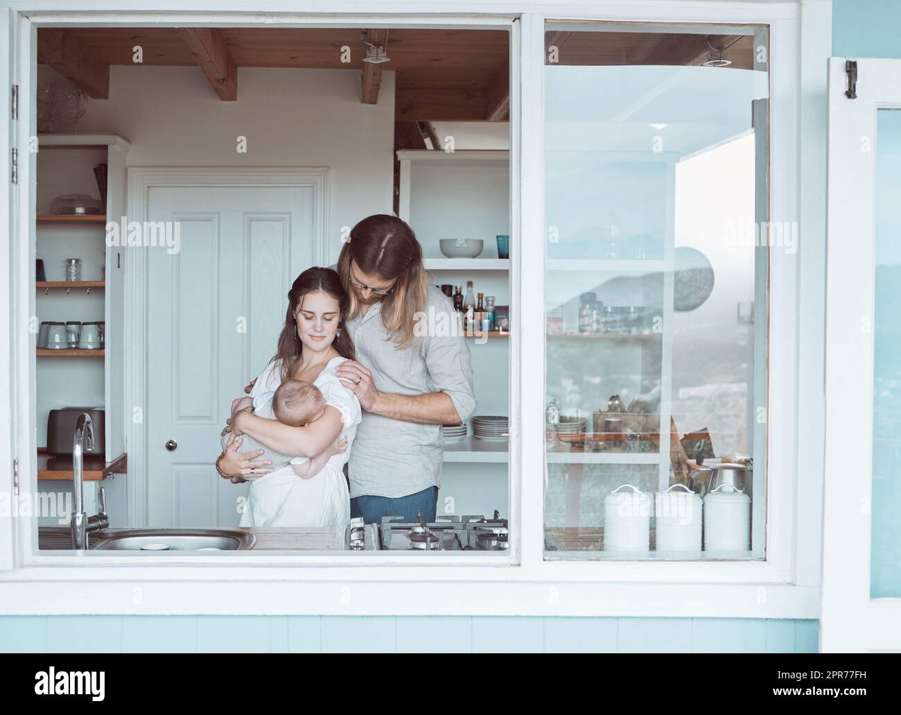 Kein Mangel an Liebe hier. Aufnahme einer jungen Familie, die ihr Neugeborenes liebevoll in der Küche zu Hause hält. Stockfoto