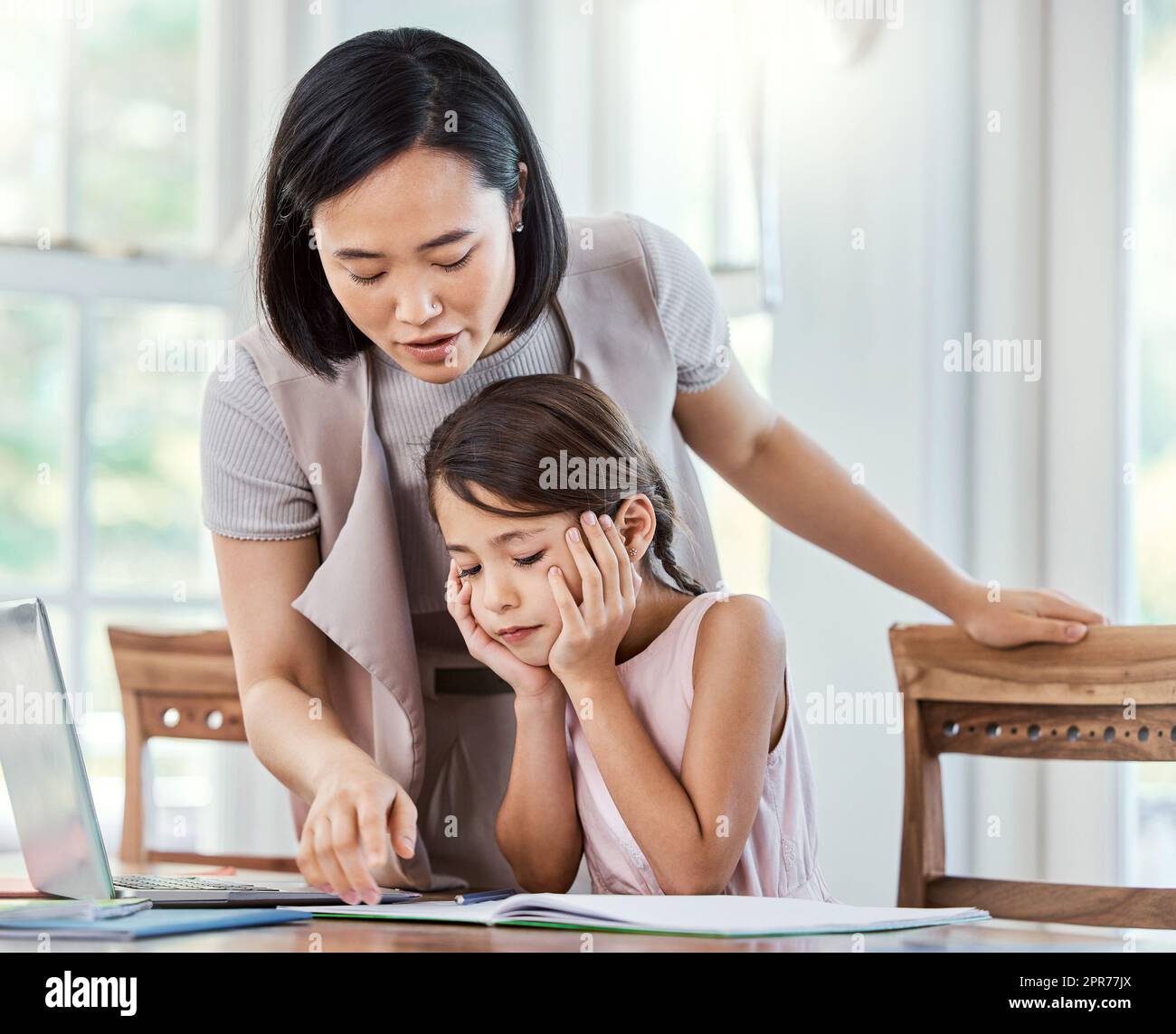 Harte Zeiten machen harte Menschen. Aufnahme einer jungen Mutter, die ihrer Tochter bei ihren Hausaufgaben zu Hause hilft. Stockfoto